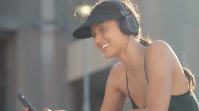 4k视频片段，一名妇女坐在外面时使用手机并戴着耳机