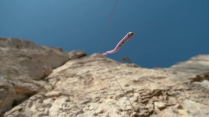自下而上，dop: 蓝色和红色的绳索悬挂在高耸的悬崖顶部。