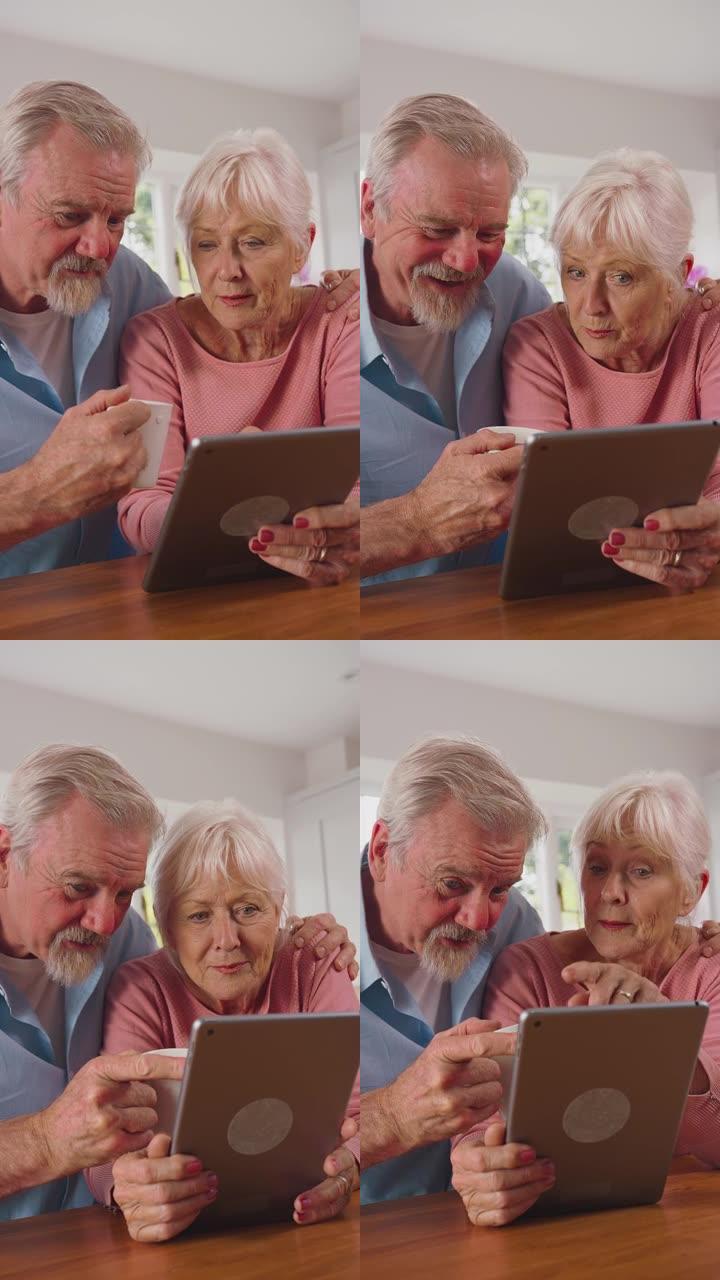 退休的高级夫妇在家里用数字平板电脑在线厨房购物或预订假期的垂直视频-慢动作拍摄
