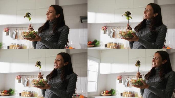 孕妇享受美味的蔬菜沙拉在厨房里吃午饭