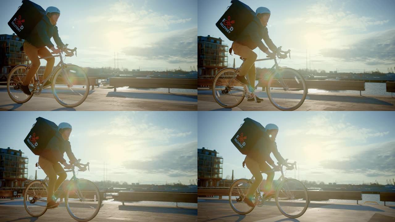 快乐食品配送快递员穿着保暖背包骑着自行车在路上为客户配送订单和包裹。阳光明媚的日子，城市附近有时尚的