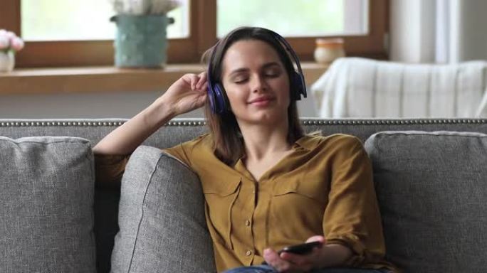 女人通过智能手机上的无线耳机收听喜欢的音乐