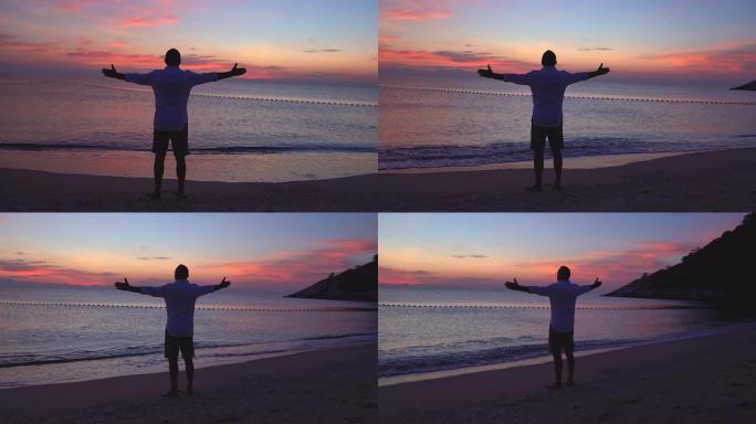 一位退休的老人张开双臂站在沙滩上呼吸早晨的空气。它意味着希望，孤独，或者独自生活的快乐。