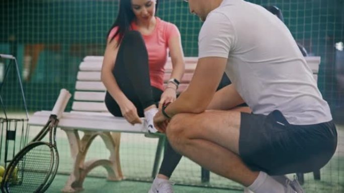 年轻的男教练帮助坐在长凳上的女性穿鞋