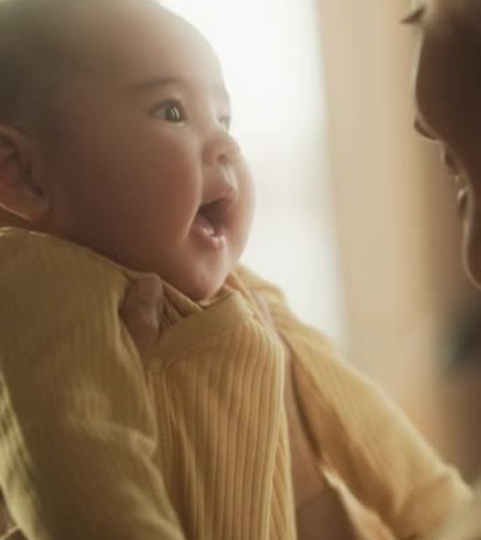 垂直屏幕:一个初为人母的亚洲女性早上在家和她可爱的宝宝玩耍的真实镜头。母亲和婴儿的温馨氛围。键时刻