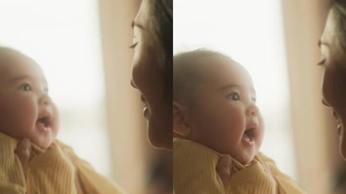 垂直屏幕:一个初为人母的亚洲女性早上在家和她可爱的宝宝玩耍的真实镜头。母亲和婴儿的温馨氛围。键时刻