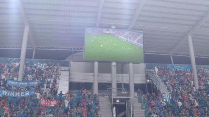 足球足球锦标赛体育场比赛，记分牌屏幕显示进球的重复。一群球迷欢呼，尖叫，玩得开心。体育频道电视广告播