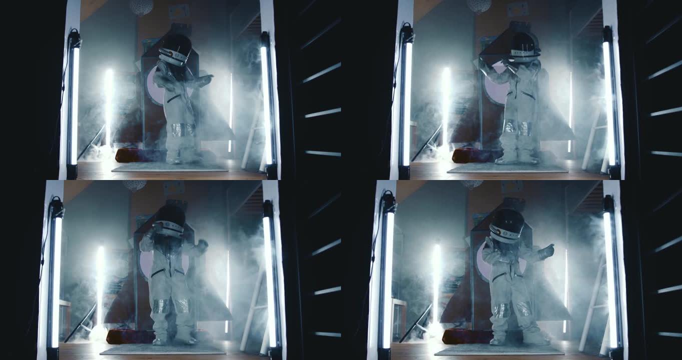 电影放大了快乐的太空人儿童在黑暗的房间里穿着宇航员服跳舞的灯光，在他的火箭船上冒烟。