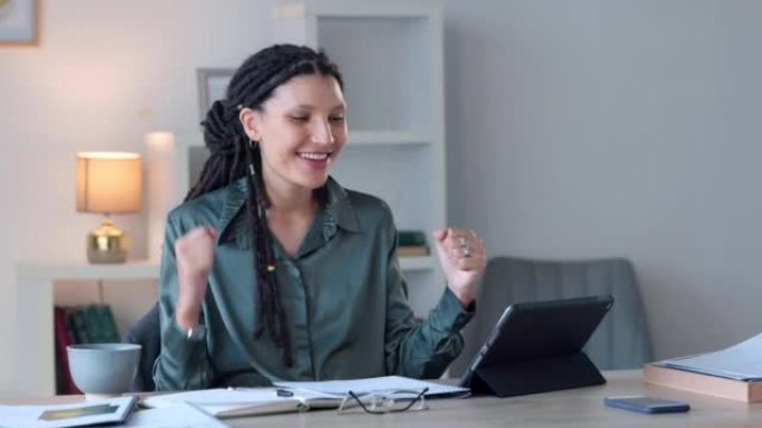 快乐的女商人庆祝好消息，同时在现代办公室的数字平板电脑上阅读信息。年轻女性对批准的贷款感到兴奋。女士