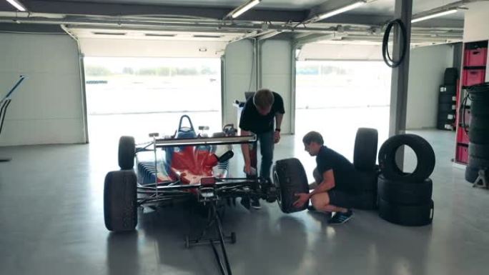 两名男子正在修理赛车的车轮