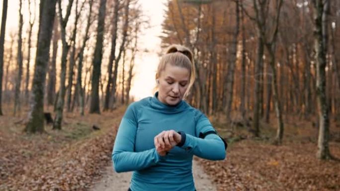 SLO MO女人在开始在森林里慢跑之前设置了健身追踪器