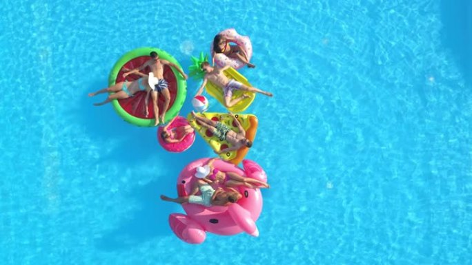 无人机: 一群朋友在游泳池旁闲逛，在有趣的漂浮物上放松