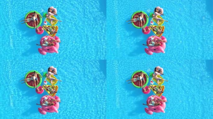 无人机: 一群朋友在游泳池旁闲逛，在有趣的漂浮物上放松