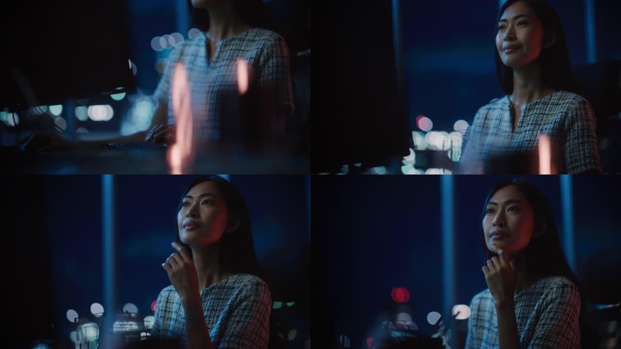 美丽的亚洲女性肖像在黑暗现代办公室的台式电脑上工作。女商人晚上很晚在家工作。成年女性使用社交媒体，键