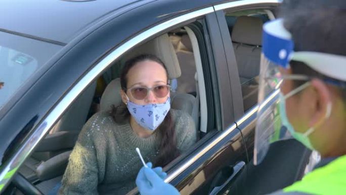 医疗专业人员在车里拿一个女人的鼻拭子