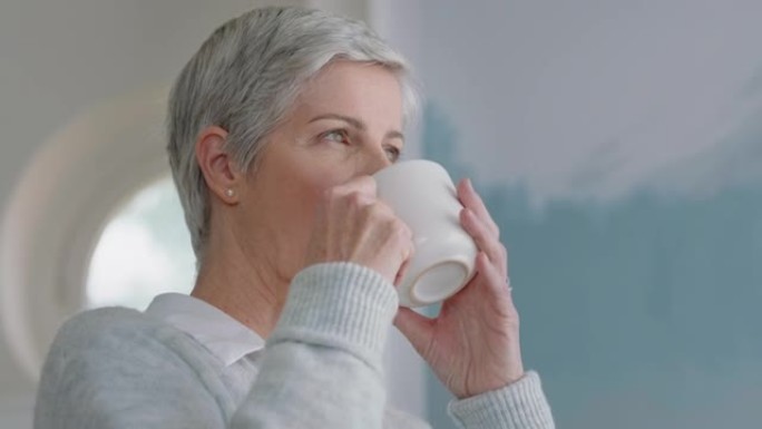 快乐的成熟女人在家喝咖啡，看着窗外享受退休生活方式，沉思着提前4k