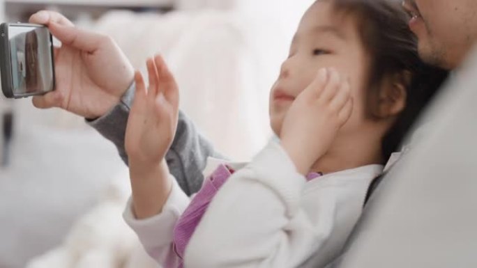 亚洲父亲和孩子使用智能手机进行视频聊天小女孩挥舞着分享周末与爸爸享受手机与朋友4k聊天