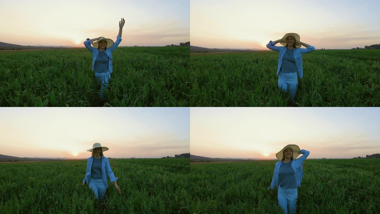 慢动作特写看日落时一名戴着草帽的美丽年轻女子在麦田里奔跑跳跃
