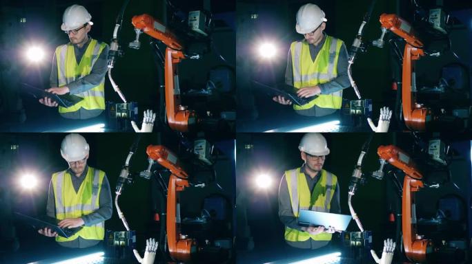 男性研究人员在安全磨损正在观察一个机器人设备，仿生臂。