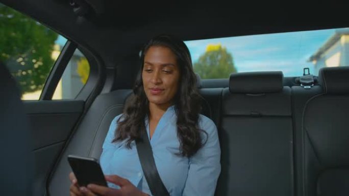 成熟的女商人坐在出租车或汽车后座上查看手机上的信息
