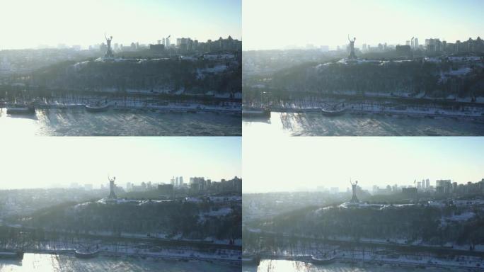 在日出的阳光下，寒冷的冬日，基辅的乌克兰国旗和祖国纪念碑的美丽空中风景。