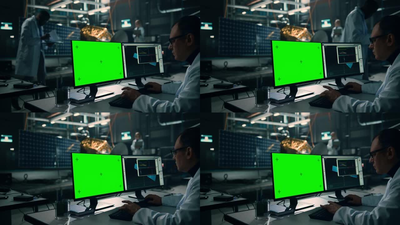 男工程师使用绿屏模拟显示计算机分析卫星。航空航天局制造设施: 科学家开发，组装用于太空探索任务的航天