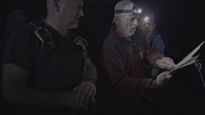 SLO MO由三个徒步旅行者组成的小组在看地图时使用大灯