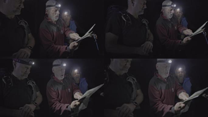 SLO MO由三个徒步旅行者组成的小组在看地图时使用大灯
