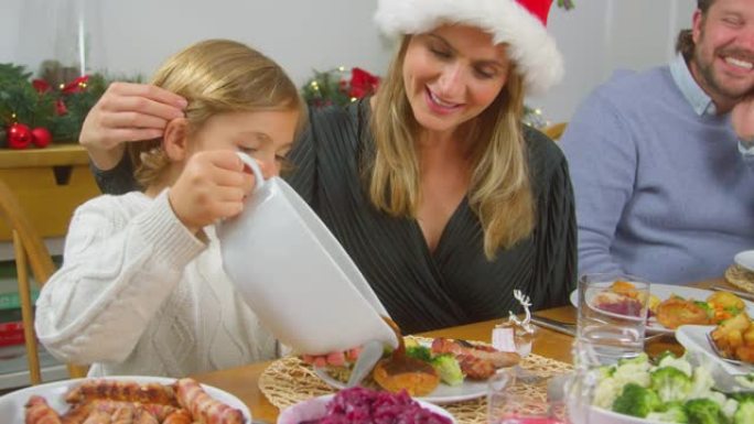 家人吃圣诞大餐时，儿子将肉汁倒在他的食物上
