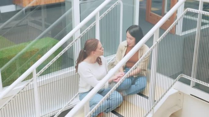 朋友，妇女坐在公寓楼的楼梯上聊天，分享生活危机中的建议和支持。信任，帮助和悲伤的女人与朋友一起在屋外