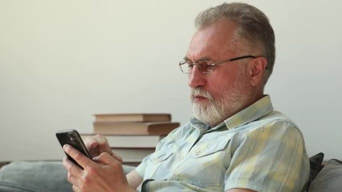 专注成熟的祖父在眼镜手持手机使用应用程序