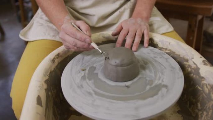在陶艺工作室使用循环工具整理陶器的女性陶工中段