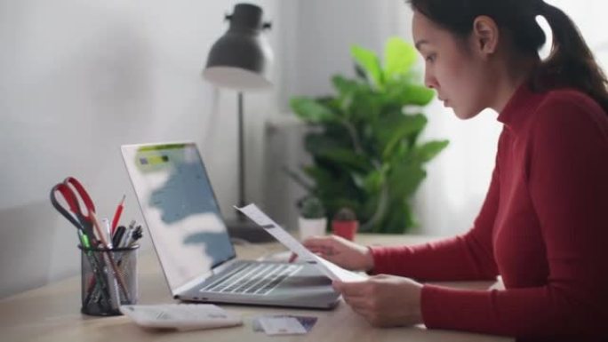 亚洲妇女在笔记本电脑上在线支付账单