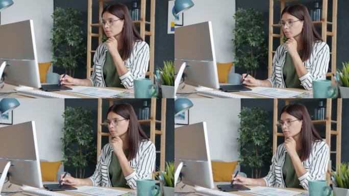 用平板电脑看着电脑屏幕设计智能手机应用的年轻女性绘画的慢动作