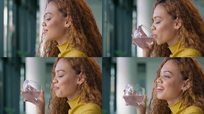 一个快乐的年轻黑人妇女在家里喝着干净的水，微笑着。女性专注于补水和补充白天流失的电解质，改善大脑，肌