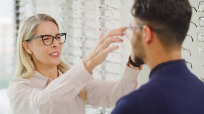 配镜师在验光期间帮助客户选择眼镜。男性顾客咨询验光师，配戴眼镜以矫正视力或改善视力
