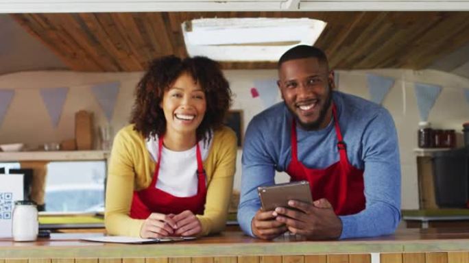 非裔美国夫妇穿着围裙在食品卡车上微笑的肖像