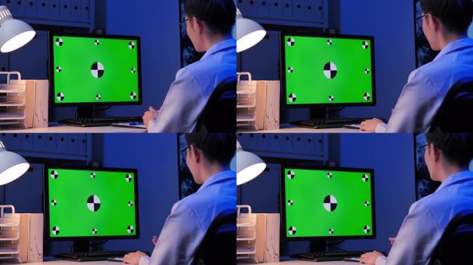 亚洲男医生在晚上工作到很晚的时候在家用电脑远程定位视频会议时看绿屏。家里绿屏