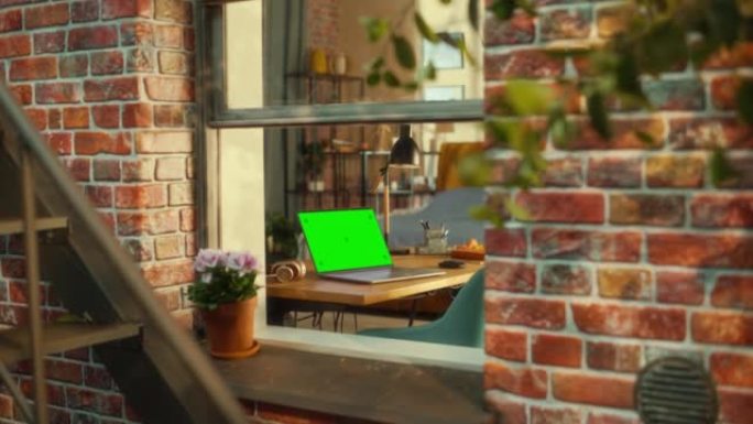 带绿屏模拟显示器的笔记本电脑站在时尚客厅的桌子上。从窗外可以看到布鲁克林风格的褐砂石多层建筑。在家工