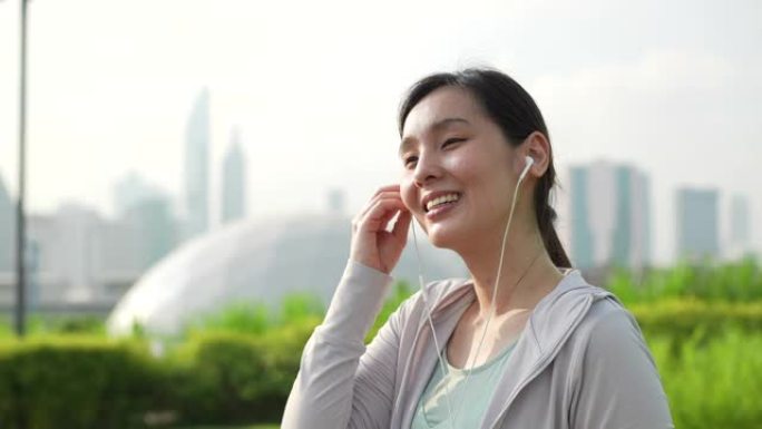 年轻的亚洲妇女在户外锻炼时听音乐