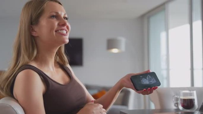 微笑孕妇在家拿着手机用超声波扫描婴儿
