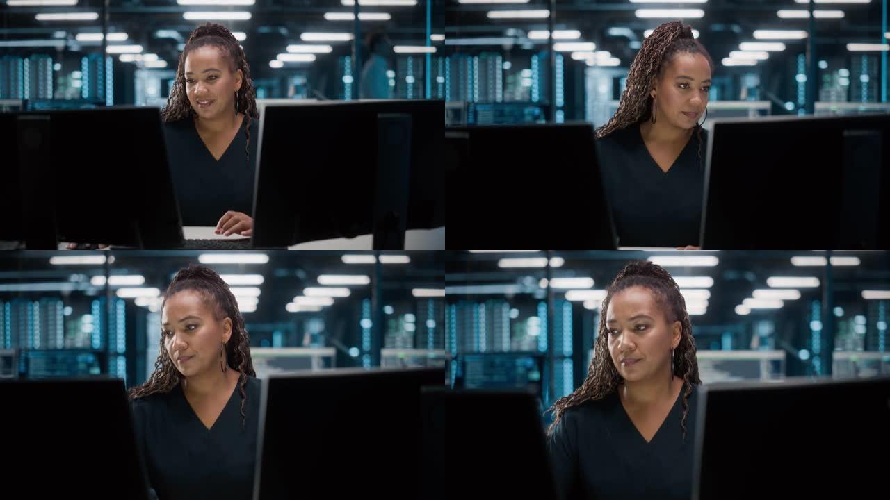 非裔美国女性IT专家在数据中心桌面工作的肖像。系统管理员工作于Web服务、云计算、服务器分析、网络安