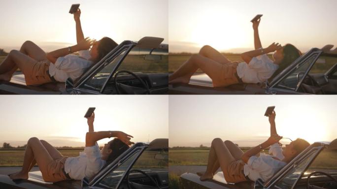 SLO MO年轻女子躺在汽车引擎盖上自拍