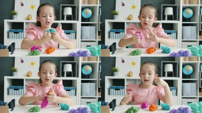 可爱的小女孩的肖像录制有关playdough的视频，然后显示竖起大拇指并挥舞着博客