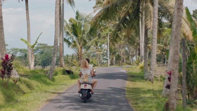 热带岛屿上骑摩托车的旅游夫妇快乐的女人举起双臂庆祝自由，享受与男朋友骑摩托车旅行的假期公路旅行