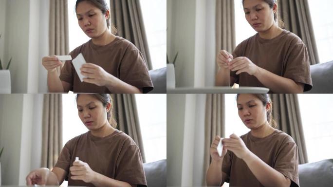 女人呆在家里，自己使用抗原测试试剂盒进行新型冠状病毒肺炎测试