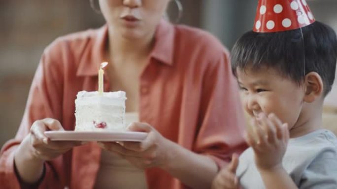 亚洲生日男孩在蛋糕上吹蜡烛