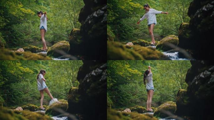 SLO MO年轻女子在溪流边的一块岩石上旋转时玩得很开心