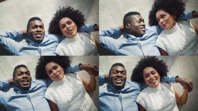 黑人妇女与丈夫躺在地板上时指着丈夫并与他交谈的电影镜头。恋爱中的情侣拥抱。俯视图，慢动作
