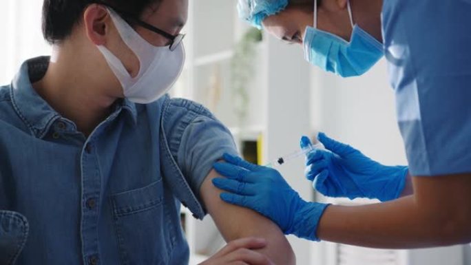 年轻的亚洲女护士给新型冠状病毒肺炎或流感抗病毒疫苗注射给高级男性患者戴上口罩，防止健康诊所的病毒疾病